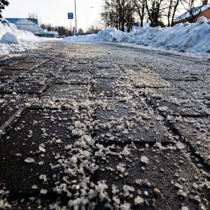 salt,grains,on,icy,sidewalk,surface,in,the,winter.,applying