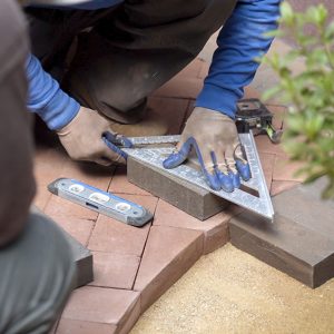 closeup,of,man,measuring,a,red,brick,paver,for,cutting